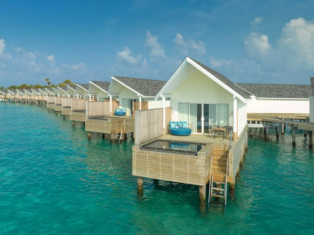 RAAYA by Atmosphere, Water Villa with Pool row of white-walled pitched-shingle-roof villas with private plunge pools, lagoon ladders and turquoise beanbags, Raa Atoll, Maldives