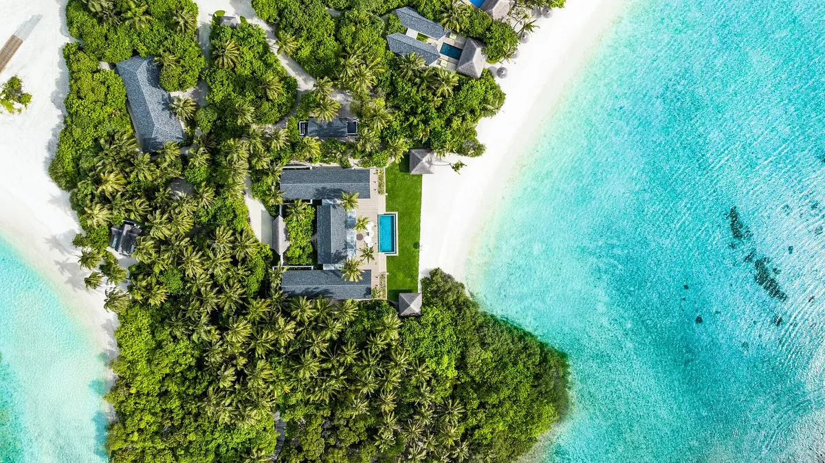 RAAYA by Atmosphere, top-down aerial of RAAYA Residence multi-pavilion configuration at island tip with garden, plunge pool and dual-beach peninsula, Raa Atoll, Maldives