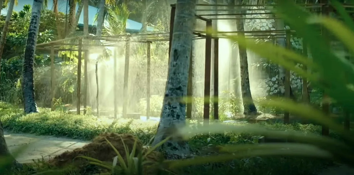 Amilla Maldives, setting, Baa Atoll, Maldives, Mystique Garden landscape feature with the cascading water-curtain installation between the open-frame timber pavilion supports and the palm-trunk grove in dense vegetation.