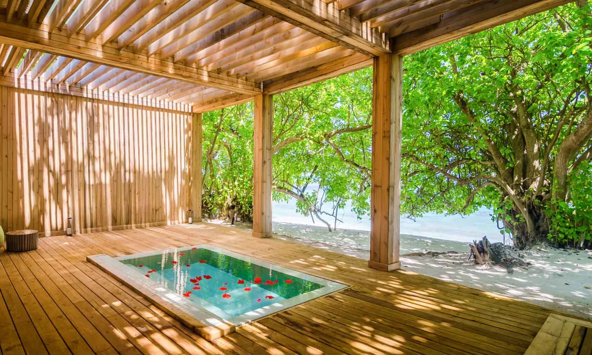 Amilla Maldives, spa, Baa Atoll, Maldives, AquaCentro spa hydrotherapy plunge in a natural-wood pavilion with the rib-trellis ceiling and screened wall, sunken rectangular cold plunge with mosaic blue tile scattered with red rose petals.