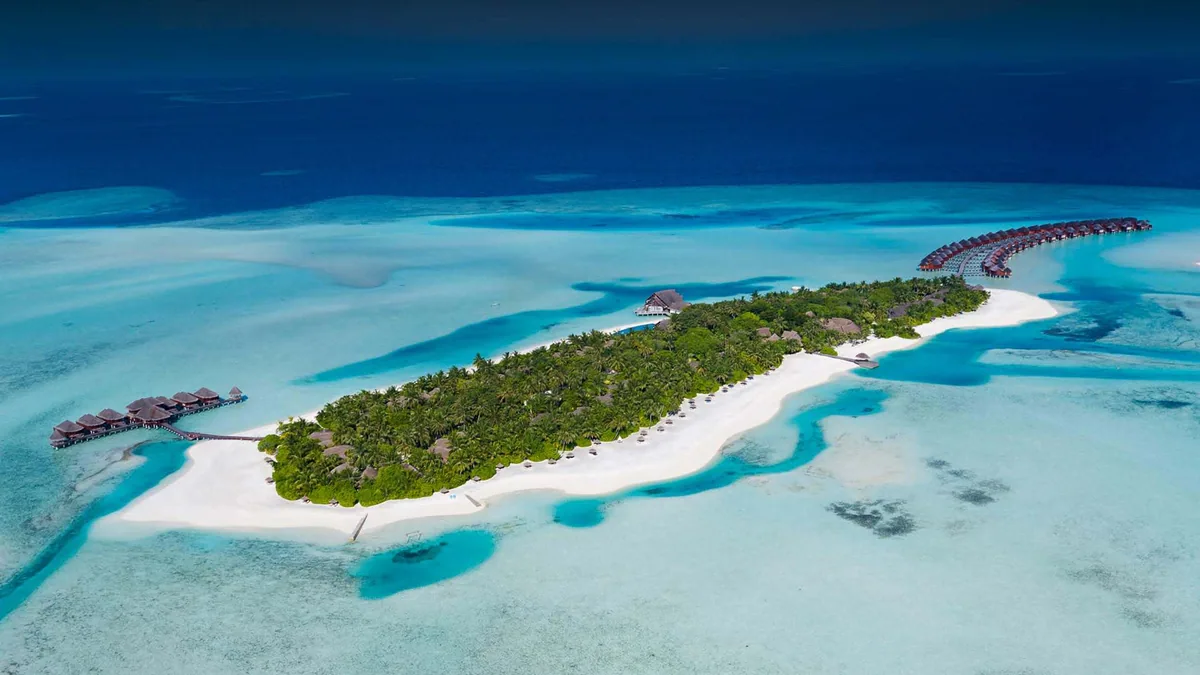 Anantara Dhigu Maldives Resort, aerial, South Malé Atoll, Maldives, Anantara Dhigu Maldives Resort, the Dhigufinolhu island geometry in northern South Malé Atoll with the over-water cluster on the lagoon side and the perimeter beach configuration; adjacent Veligandu Huraa (Anantara Veli) visible to the north.