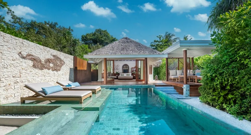 Anantara Kihavah Maldives Villas, villa beach, Baa Atoll, Maldives, Beach Pool Villa with a carved manta-ray relief in the stone garden wall, thatched-roof living pavilion with daybed, twin sun loungers on the sunken pool deck, secondary daybed pavilion, dense jungle screening the perimeter.