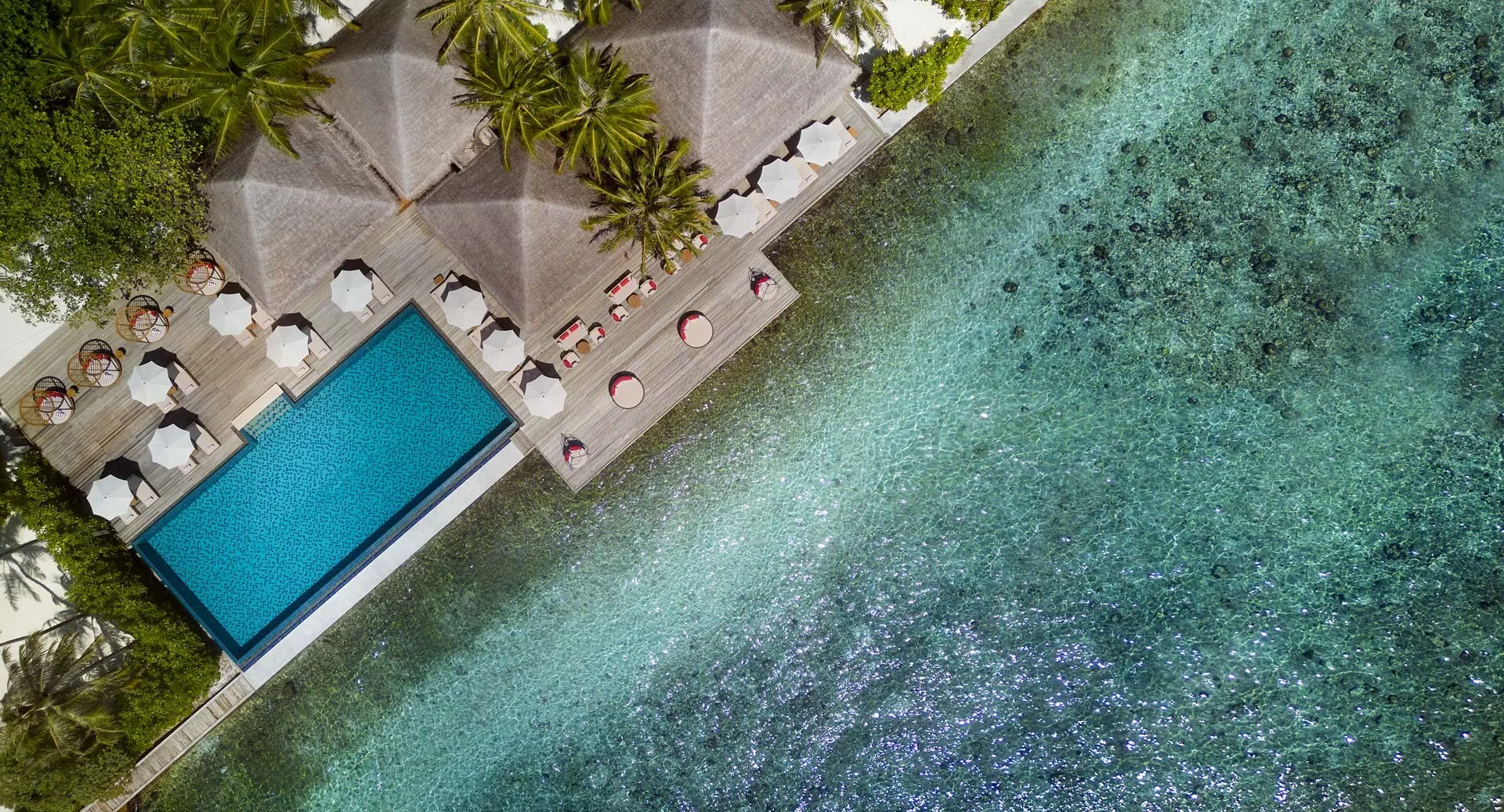 Anantara Veli Maldives Resort, dining, South Malé Atoll, Maldives, Dhoni Bar aerial, thatched-roof pavilion fronting the lagoon with an open-air swimming pool and parasol cluster, the day-time lagoon-side venue converted from a traditional dhoni configuration.