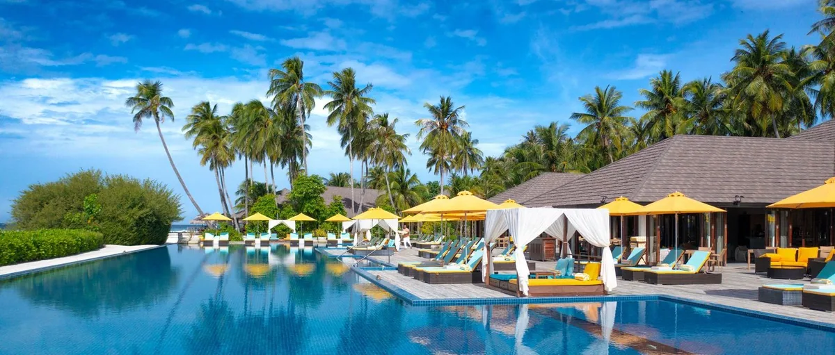 Atmosphere Kanifushi Maldives, dining, Lhaviyani Atoll, Maldives, The Liquid pool bar deck with yellow umbrellas, white cushioned cabanas, and the infinity-edge pool fronting the lagoon.