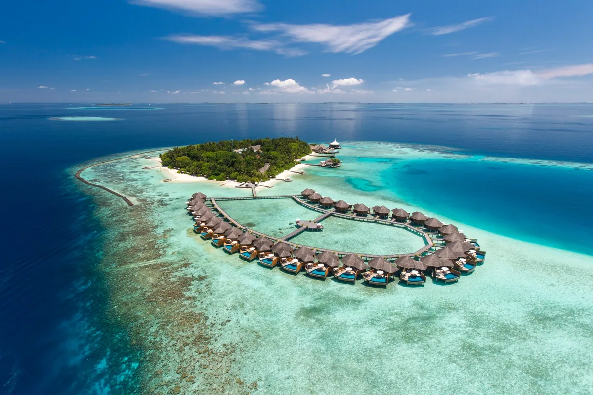 Baros Maldives, aerial, North Malé Atoll, Maldives, Baros Maldives, the compact 600-metre Baros island geometry roughly 11 km west of Velana International with the lagoon-side over-water jetty and the Lighthouse Restaurant arrival approach.