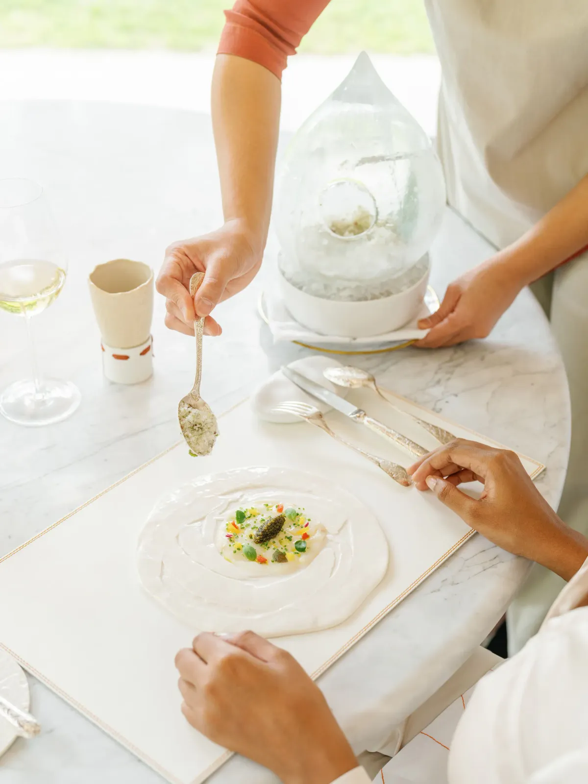 Chef finishing a caviar-topped amuse on a marble counter at Le 1947 restaurant, Cheval Blanc Randheli.