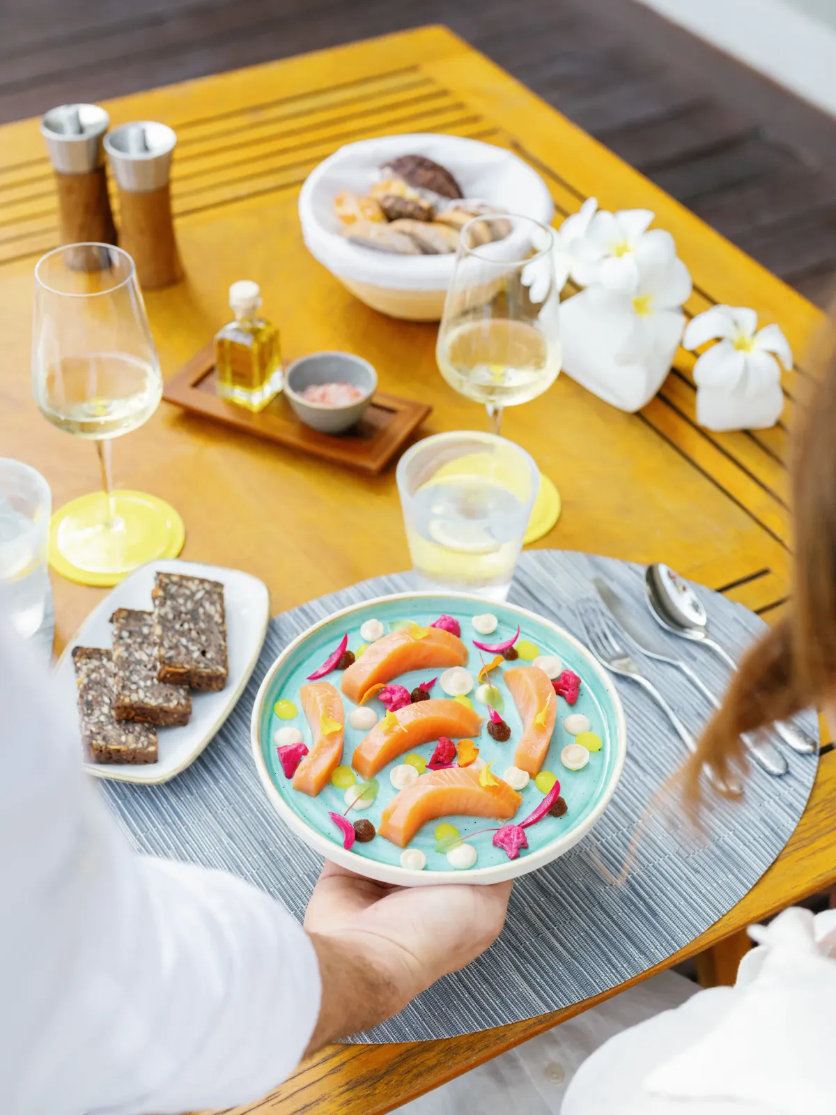 In-villa terrace lunch service at Cheval Blanc Randheli, salmon plated on a turquoise dish with frangipani and white wine.