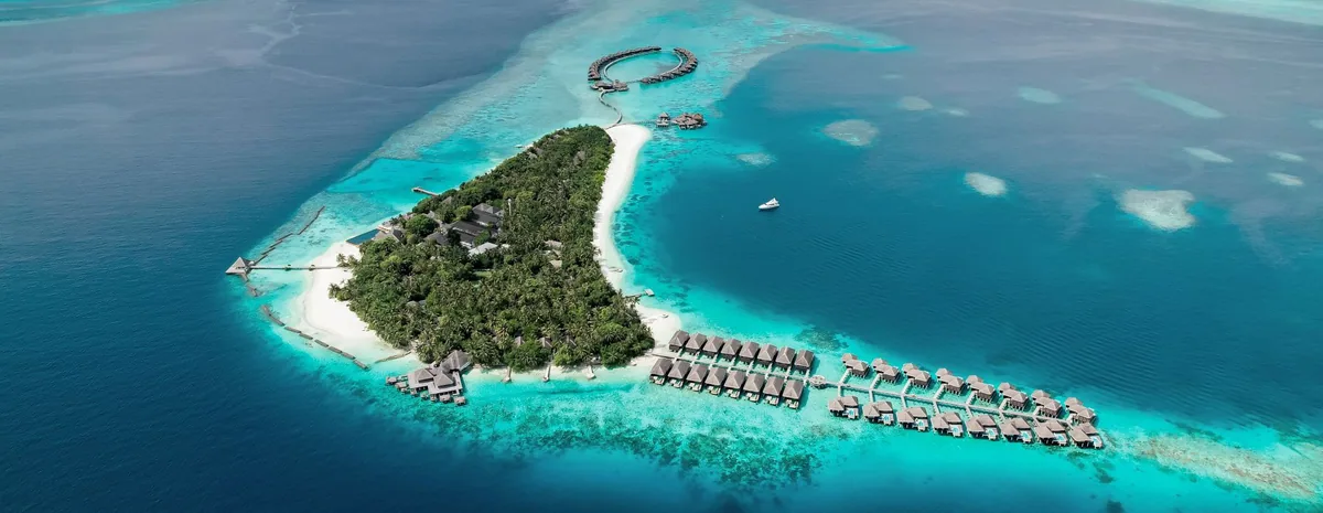 Coco Bodu Hithi, aerial, North Malé Atoll, Maldives, Coco Bodu Hithi, the Bodu Hithi natural-island geometry on the northern edge of North Malé Atoll with the over-water jetty cluster and the Aqua restaurant lagoon-traverse approach.