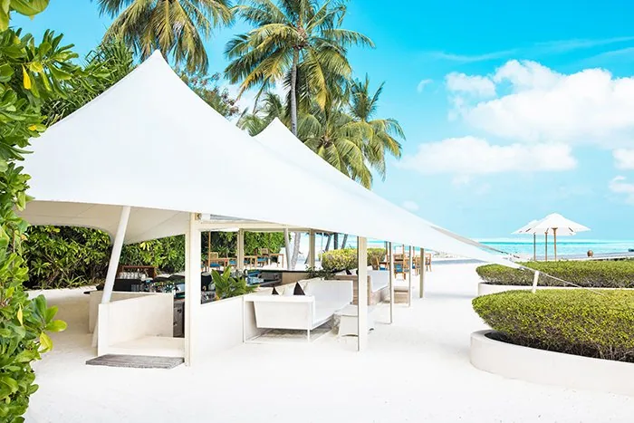 Conrad Maldives Rangali Island, setting, Alif Dhaal (South Ari) Atoll, Maldives, Quiet Zone Beach Bar on Rangali Island, white-canopy tented lounge fronting the lagoon with daybeds and a stocked counter, the adults-only social anchor that holds the over-16 zone together.
