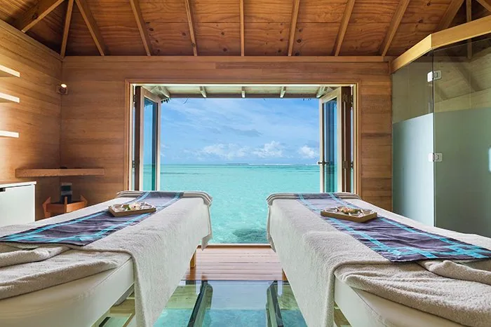 Conrad Maldives Rangali Island, spa, Alif Dhaal (South Ari) Atoll, Maldives, Couples treatment room with the in-floor glass panel under the twin massage beds, sliding timber doors opening directly onto the lagoon, a signature configuration of the Over Water Spa.