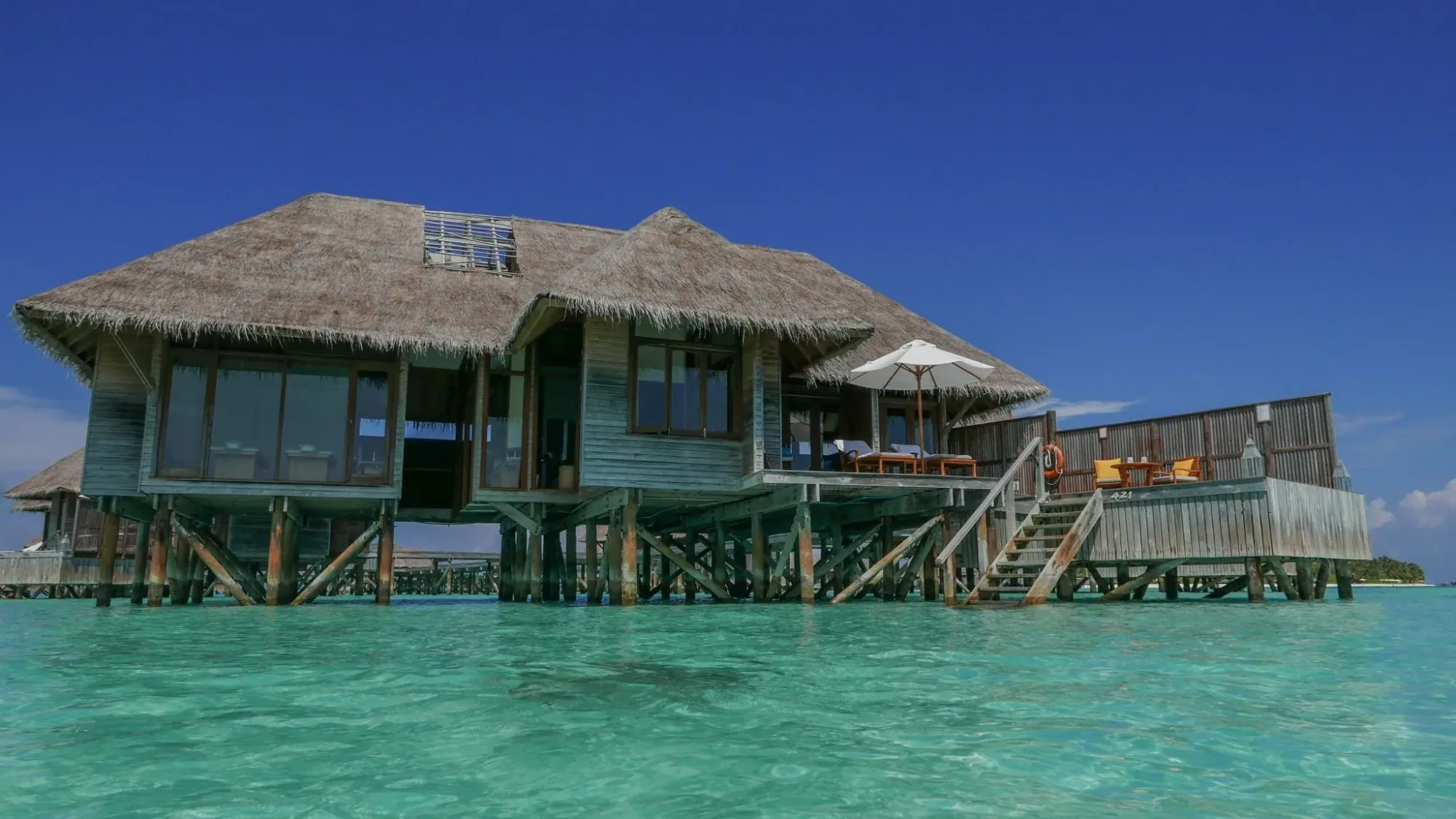 Conrad Maldives Rangali Island, villa overwater, Alif Dhaal (South Ari) Atoll, Maldives, Retreat Water Villa exterior, thatched-roof villa on timber stilts above the lagoon, side staircase down to the swimming step, the chain-luxury overwater configuration on Rangali.