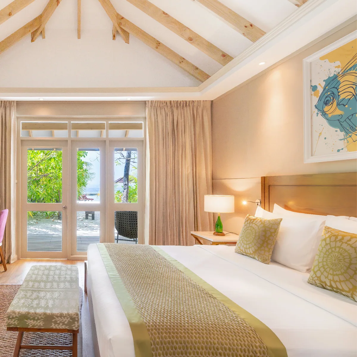 Cinnamon Ellaidhoo Maldives, villa beach, Alif Alif Atoll (North Ari), Maldives, Beach Bungalow interior with the warm-wood vaulted-rafter ceiling, the chartreuse and tropical-fish artwork along the wall, the white linen on the king bed framed by the Cinnamon brand-signature interior palette.