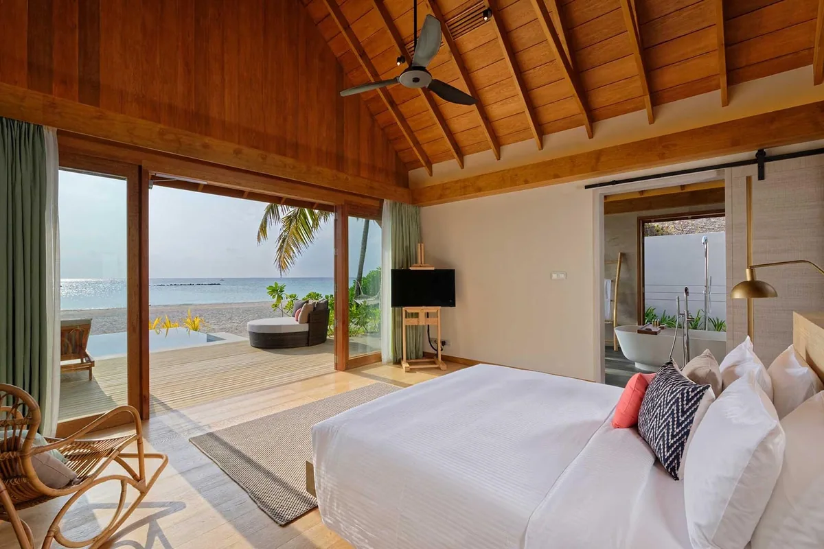 Emerald Faarufushi, Beach Villa with Pool interior with warm-wood cathedral ceiling, king bed, glass doors to daybed and plunge pool, freestanding bathtub in bathroom, Raa Atoll, Maldives
