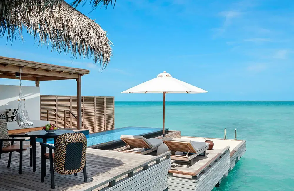 Sirru Fen Fushi Private Lagoon Resort, Grand Water Villa deck with private plunge pool, sun loungers, parasol and hammock under palm-thatched eave on the open lagoon, Shaviyani Atoll, Maldives