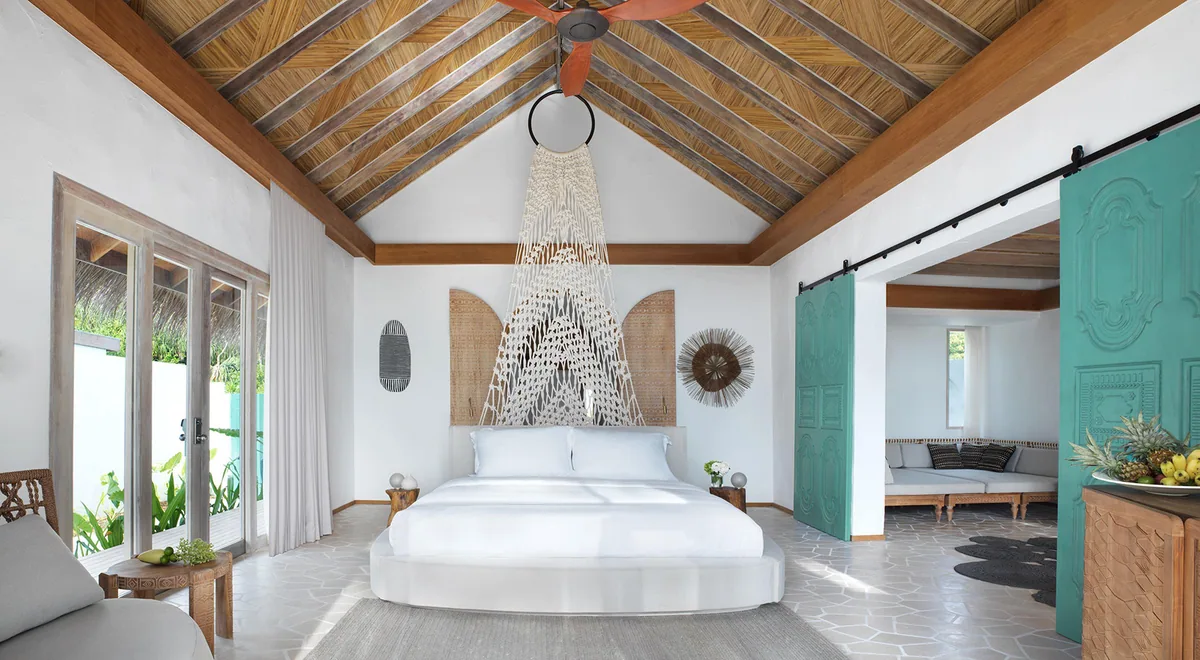 Sirru Fen Fushi Private Lagoon Resort, Jungle Pool Villa interior with turquoise barn doors, macrame canopy over king bed, palm-leaf cathedral ceiling and terrazzo floor, Shaviyani Atoll, Maldives
