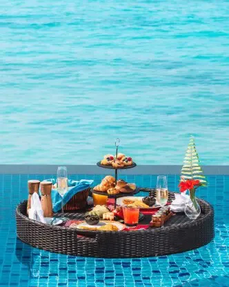 Sirru Fen Fushi Private Lagoon Resort, in-villa floating breakfast wicker tray with pastries, fruit platter and juice flutes on private plunge pool with lagoon horizon, Shaviyani Atoll, Maldives