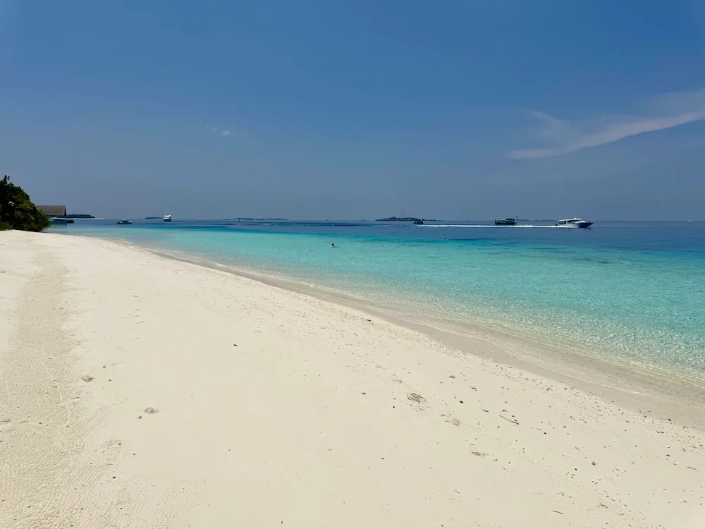Four Seasons Resort Maldives at Landaa Giraavaru, setting, Baa Atoll, Maldives, Landaa Giraavaru beach, a pristine white-sand crescent along the calm turquoise lagoon, the over-water bungalow row from the property's western edge visible on the horizon.