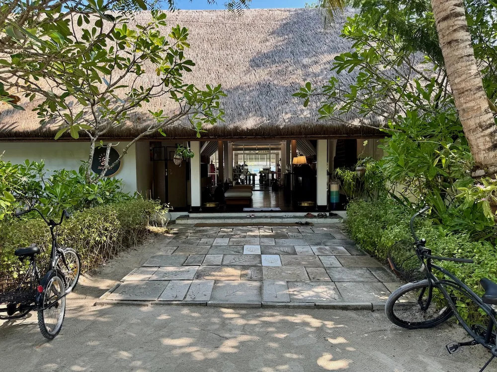 Four Seasons Resort Maldives at Landaa Giraavaru, spa, Baa Atoll, Maldives, Spa entrance: slate-tiled path leading through the palm canopy to the long thatched pavilion of the Ayurvedic Healing Centre, open vestibule with reception visible inside.