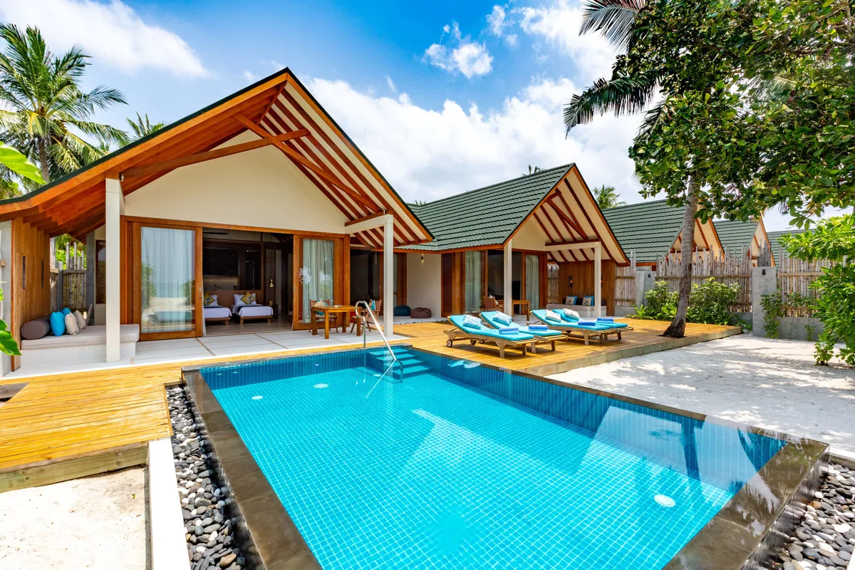Furaveri Maldives, Beach Residence two-pavilion configuration with pitched roofs, rectangular blue-tile pool, teal-cushion sun loungers and palm canopy, Raa Atoll, Maldives