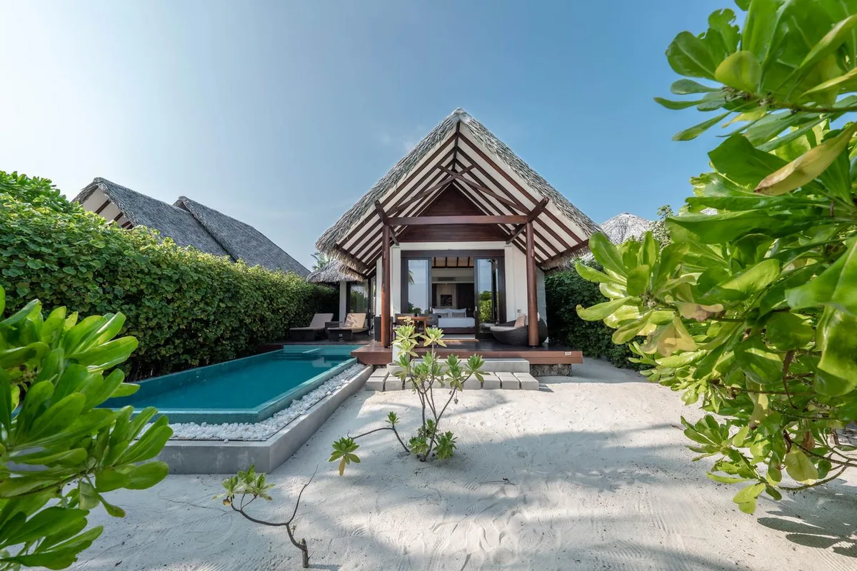 Heritance Aarah Maldives, villa beach, Raa Atoll, Maldives, Heritance Beach Villa exterior, A-frame thatched-roof pavilion fronting a turquoise-tile plunge pool, sand garden with sea-grape hedging carrying the largest-beach-villa-claim spatial footprint.