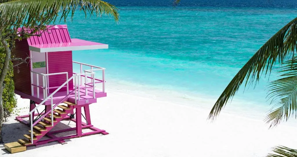 Ifuru Island Maldives, setting, Raa Atoll, Maldives, The pink Hubba Hubba sundowner tower on the 1.2-kilometre west-facing beach, raised wooden lifeguard-style platform in bright magenta with white railing, the property's signature icon along the sunset axis.