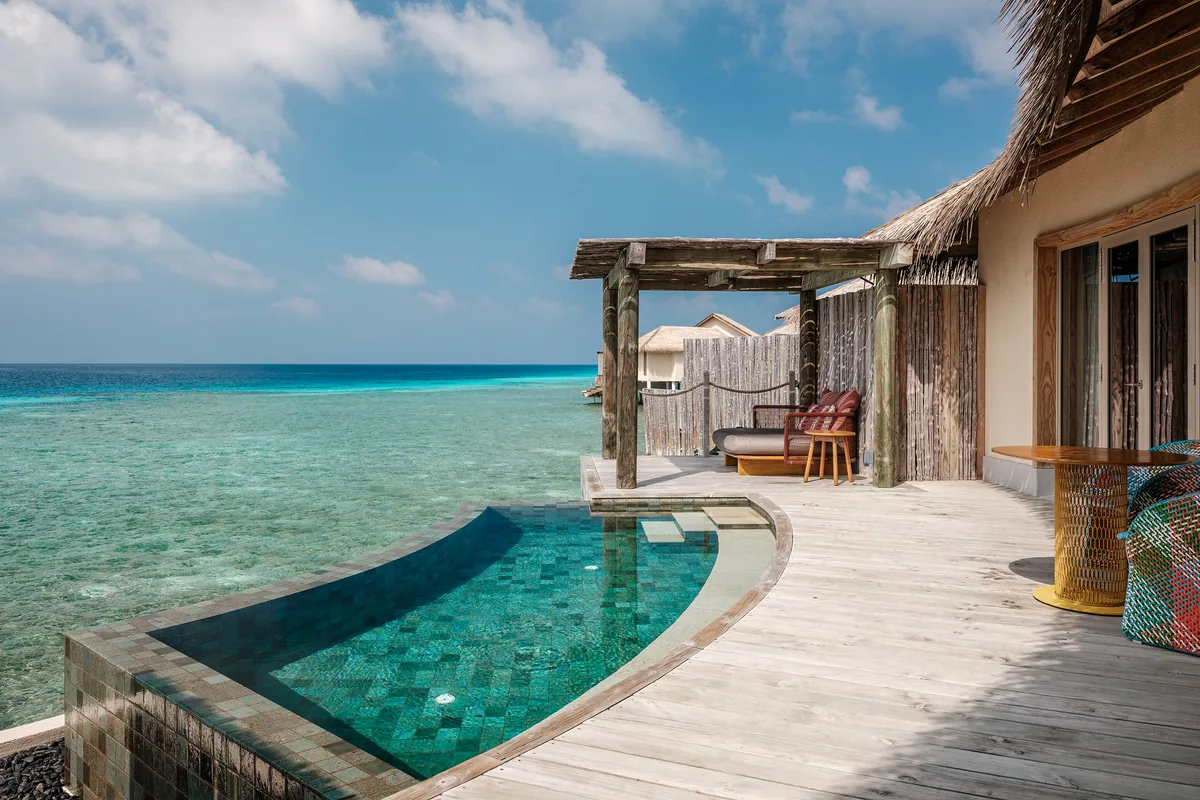 InterContinental Maldives Maamunagau Resort, villa overwater, Raa Atoll, Maldives, Overwater Pool Villa exterior deck, 215-sqm category with the signature green-mosaic plunge pool fronting the rough-hewn timber pergola, kayak racked on the deck and woven loungers facing the Maamunagau lagoon.