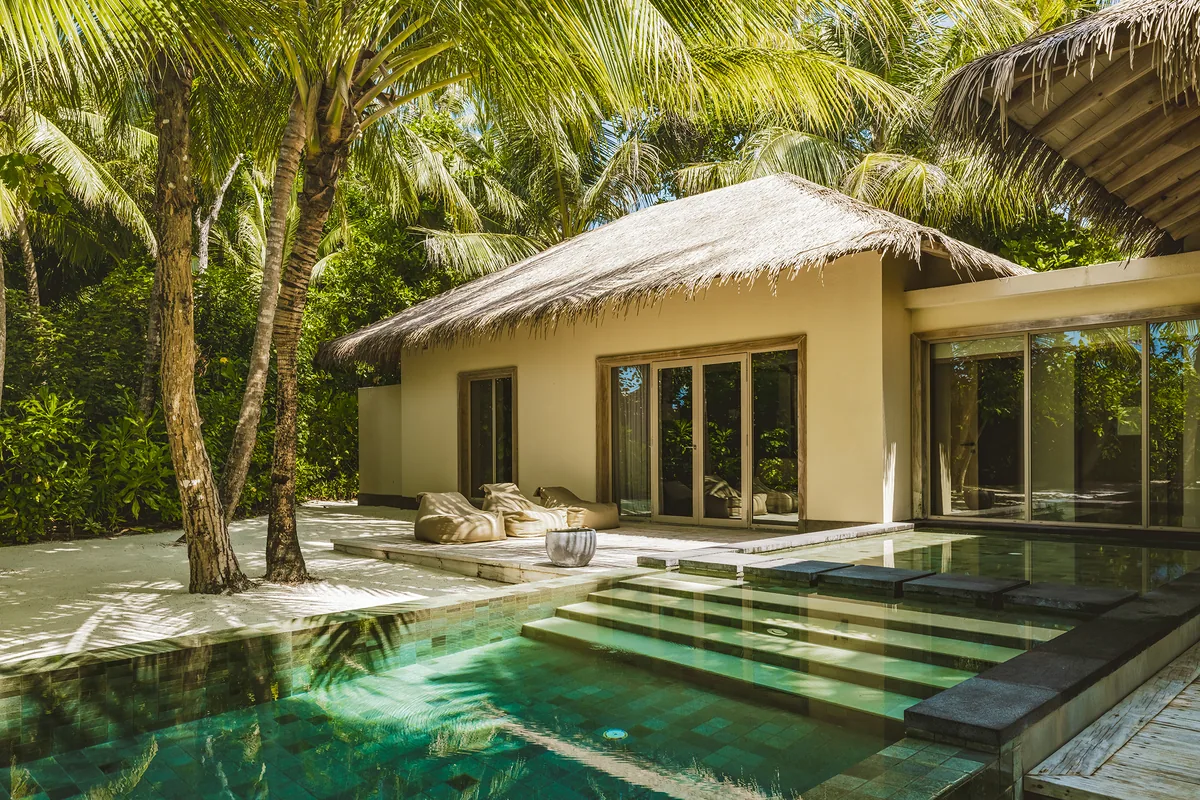 InterContinental Maldives Maamunagau Resort, villa beach, Raa Atoll, Maldives, Sunset Beach Pool Villa exterior, single-pavilion configuration with the thatched-pyramid roof above the green-mosaic step-cascade plunge pool, palm canopy framing.