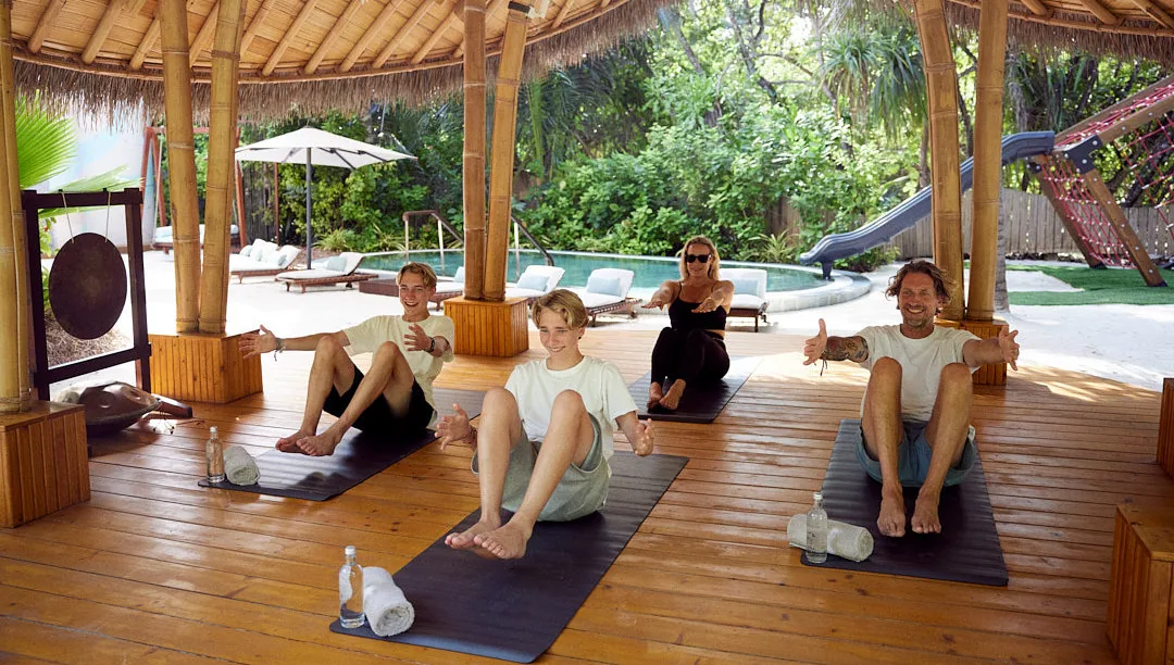 JOALI BEING, activities, Raa Atoll, Maldives, Yoga and movement session in the open pavilion, group practice on hardwood floors under the thatched canopy, one of the daily sunrise programmes anchoring the Four Pillars rhythm.