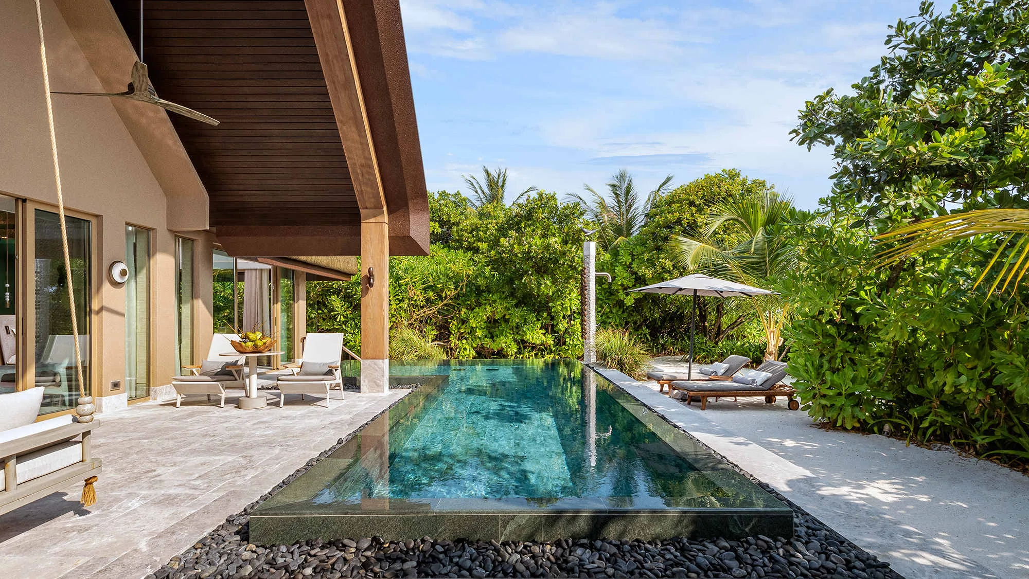 JOALI BEING, villa beach, Raa Atoll, Maldives, Beach Pool Villa, private infinity pool with sun lounger and umbrella, retractable glass wall opening from the bedroom to the deck, palm forest backdrop.