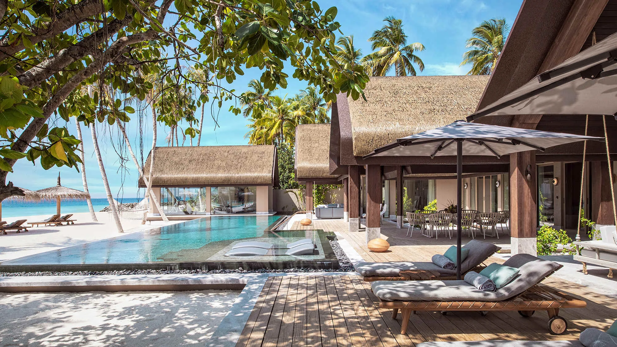 JOALI BEING, villa beach, Raa Atoll, Maldives, Three-Bedroom Wellbeing Beach Pool Residence, 345 sqm multi-bedroom anchor with private pool, dark-wood deck and twin loungers, multiple thatched wings angled across the beach frontage.
