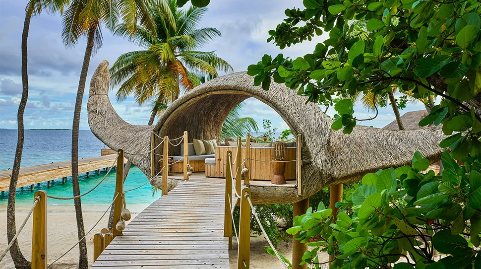 JOALI Maldives, spa, Raa Atoll, Maldives, ESPA spa pavilion conceived by Porky Hefer: the distinctive curved organic timber-and-thatch treehouse structure on the beach, accessed by a slatted timber walkway through the palm canopy.