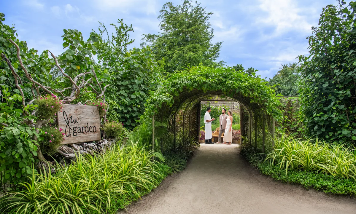 JW Marriott Maldives Resort & Spa, JW Garden entrance with driftwood signboard and vine-laden archway, Shaviyani Atoll, Maldives