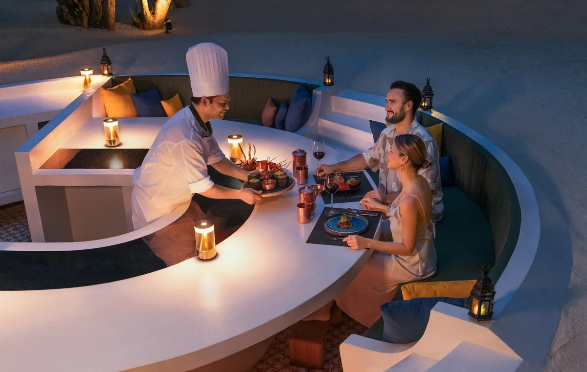 JW Marriott Maldives Resort & Spa, RIHA destination dining sunken curved-concrete amphitheatre with chef plating to couple, Shaviyani Atoll, Maldives