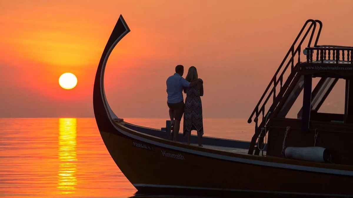 Lily Beach Resort & Spa, activities, Alif Dhaal (South Ari) Atoll, Maldives, Sunset cruise on the property-branded Himmath dhoni with the curved stem-piece silhouetted against the orange sun over the mirror-calm sea.