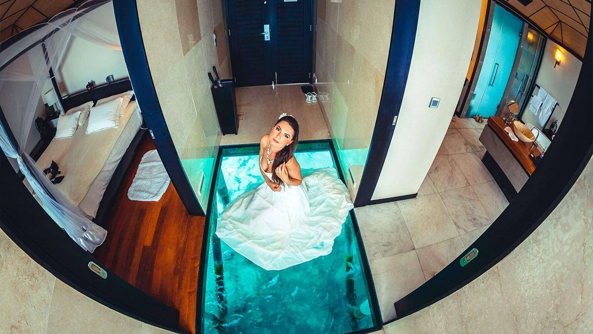 Lily Beach Resort & Spa, villa overwater, Alif Dhaal (South Ari) Atoll, Maldives, Deluxe Water Villa with the signature glass-floor panel revealing the turquoise lagoon below the living-area threshold.