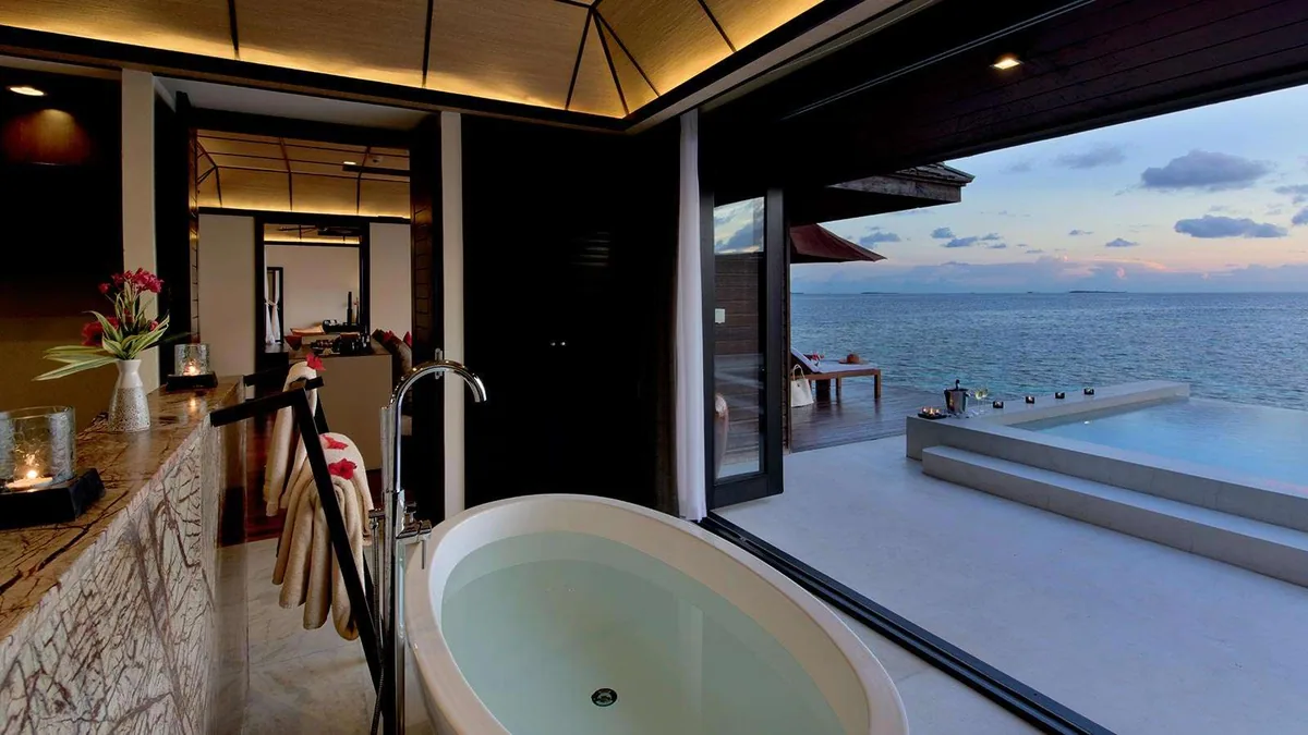 Lily Beach Resort & Spa, villa overwater, Alif Dhaal (South Ari) Atoll, Maldives, Sunset Water Villa with Pool, the freestanding oval tub at the marble-counter bath line opening to the infinity plunge pool and the dusk horizon.