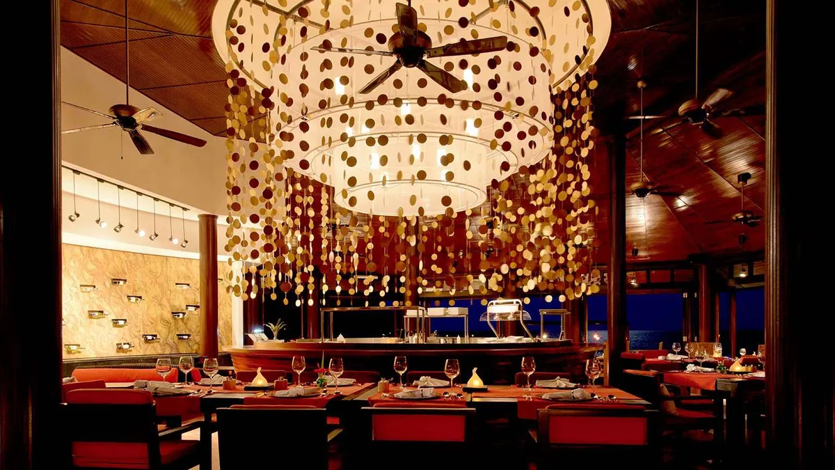Lily Beach Resort & Spa, dining, Alif Dhaal (South Ari) Atoll, Maldives, Tamarind over-water Thai venue with the signature multi-tier gold-disc cascade chandelier and the red-banquette banquet line.