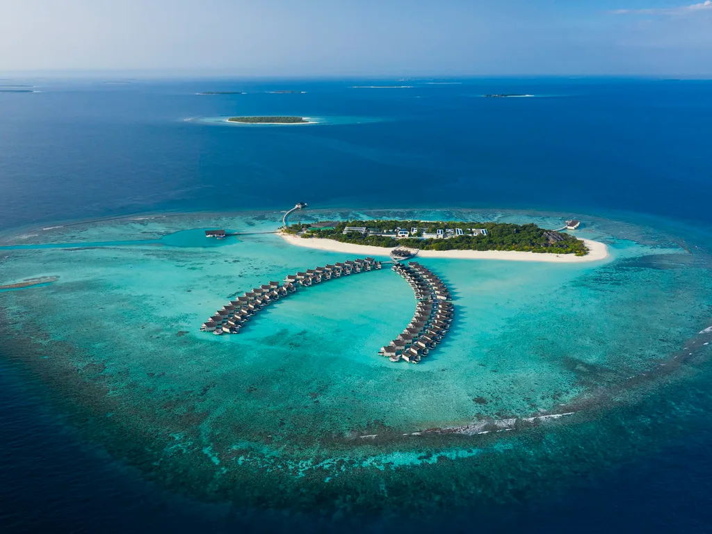 Mövenpick Resort Kuredhivaru Maldives, aerial of Kuredhivaru island with moth-wing overwater villa arcs, Noonu Atoll, Maldives