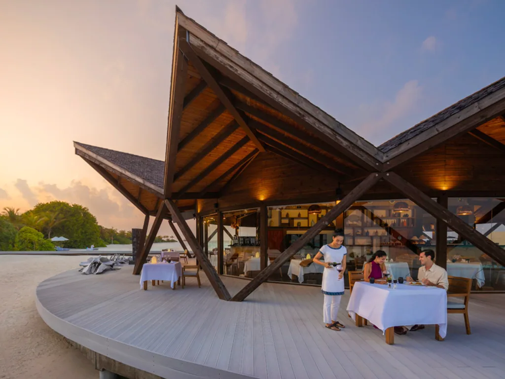 Mövenpick Resort Kuredhivaru, Bodumas angular peaked-roof beachfront pavilion at sunset, Noonu Atoll, Maldives