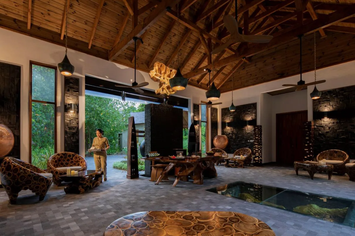 Mövenpick Resort Kuredhivaru, Zara Spa lobby with dark-textured walls, log-slice tables, exposed beams and pendant lights, Noonu Atoll, Maldives