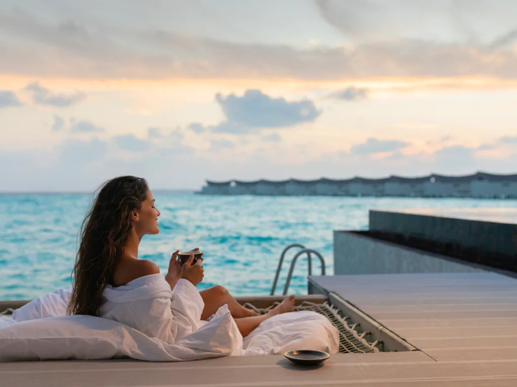 Mövenpick Resort Kuredhivaru, Overwater Pool Villa sunset hammock with OWV cluster visible across lagoon, Noonu Atoll, Maldives