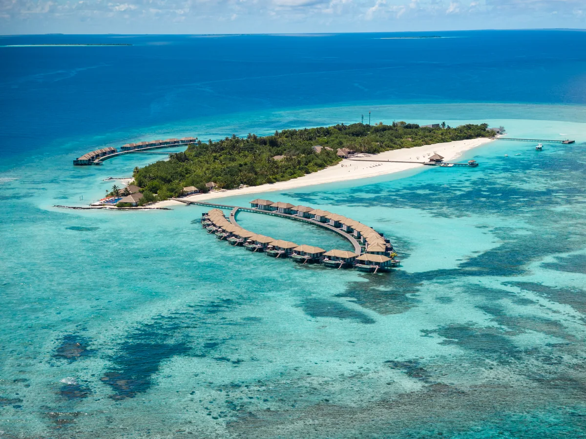 Noku Maldives, aerial of Kudafunafaru from the south showing OWV ring and arrival jetty, Noonu Atoll, Maldives