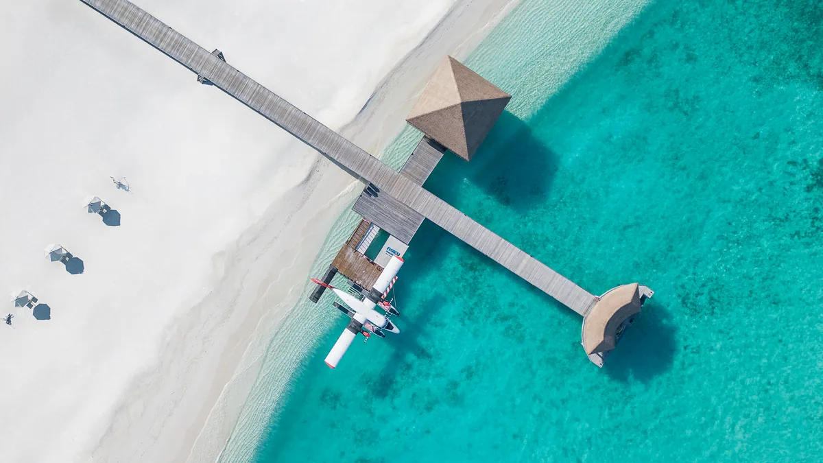 Noku Maldives, top-down aerial of the arrival jetty with Noku-branded seaplane moored, Noonu Atoll, Maldives