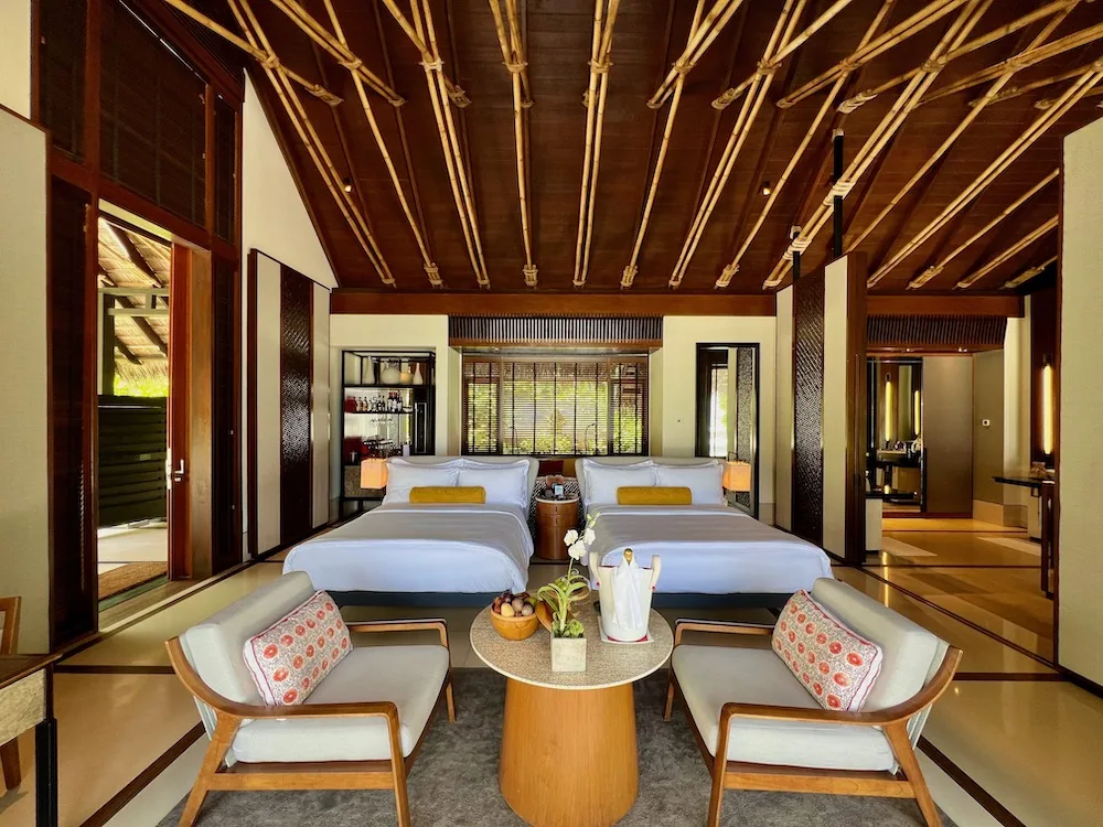 Twin-bed Beach Villa interior at One&Only Reethi Rah with bamboo-rib vaulted ceiling, mahogany trim and mustard accents.