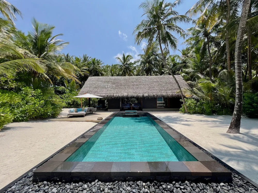 Beach Villa with private emerald-tile pool, dark wood deck and pebble border under palm canopy at One&Only Reethi Rah.