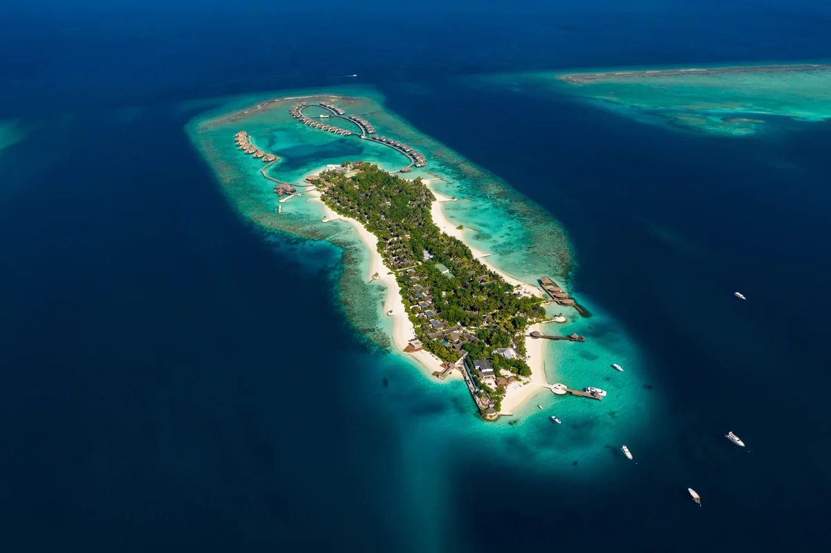 OZEN RESERVE BOLIFUSHI, aerial, South Malé Atoll, Maldives, OZEN RESERVE BOLIFUSHI, the Bolifushi island geometry in northern South Malé Atoll with the over-water cluster on the lagoon side and the perimeter beach configuration; all 90 villas with private pools by deliberate design.
