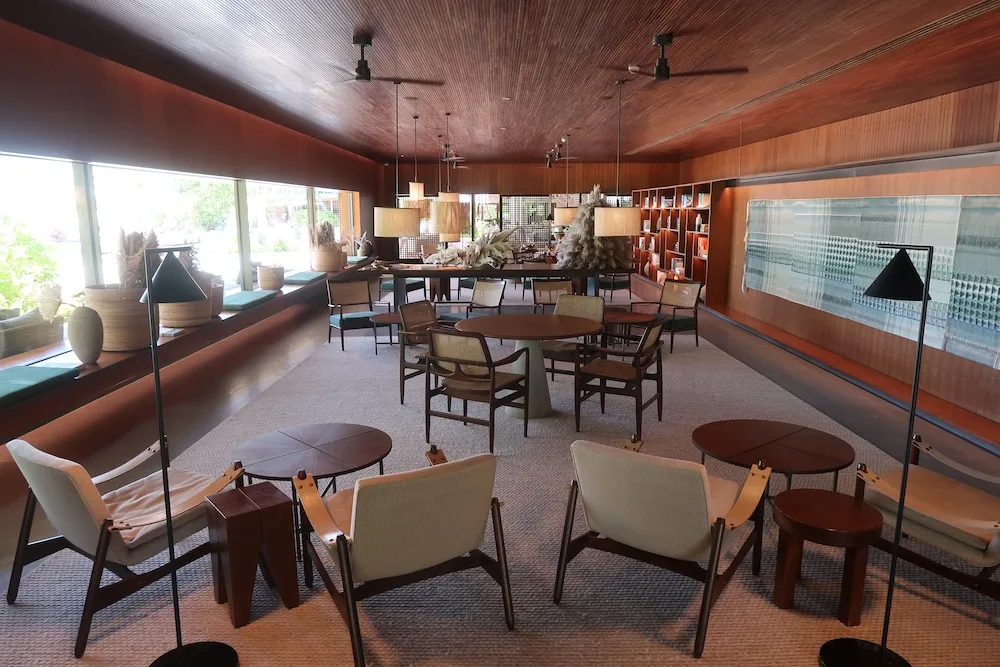 Patina Maldives, Fari Islands, lobby, North Malé Atoll, Maldives, Central lobby lounge, Marcio Kogan's MK27 vocabulary in open form: off-form concrete columns, plantation-teak ceiling, neutral linen seating clusters and the signature reeded-timber screen walls, the property's interior thesis distilled into one room.