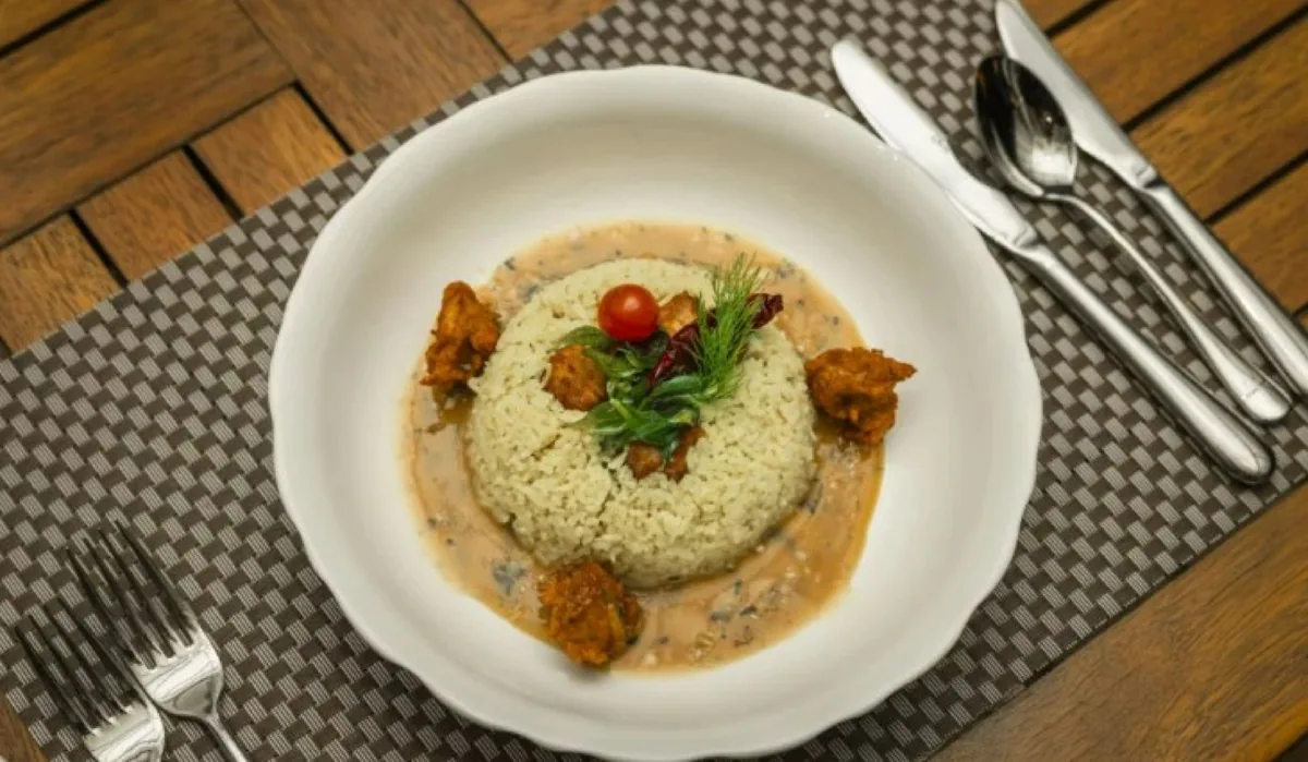 Siyam World Maldives, Kaage Maldivian plated rice with mas riha fish curry chunks in coconut-tomato gravy on dark wood table, Noonu Atoll, Maldives