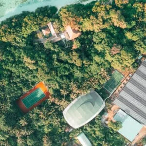 Aerial of padel and tennis courts at Soneva Fushi, set among palms.