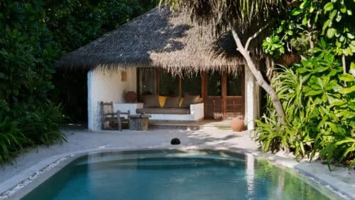 Soneva Fushi Villa Suite with pool, thatched roof and jungle greenery surround.